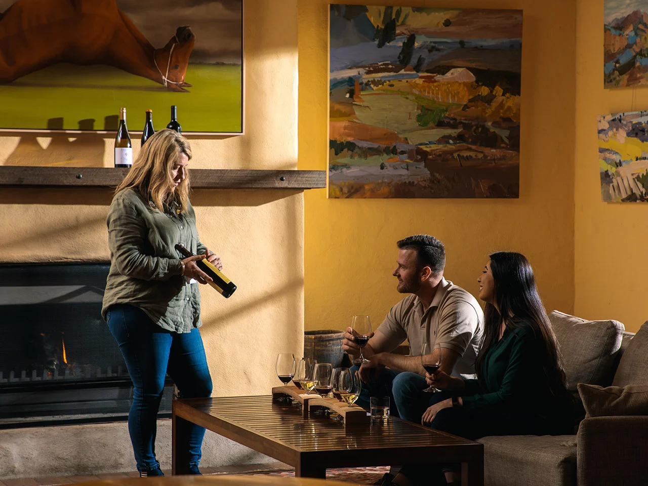 Wine ambassador presenting a tasting flight to couple seated in the Yalumba Wine Room with fireplace and artwork