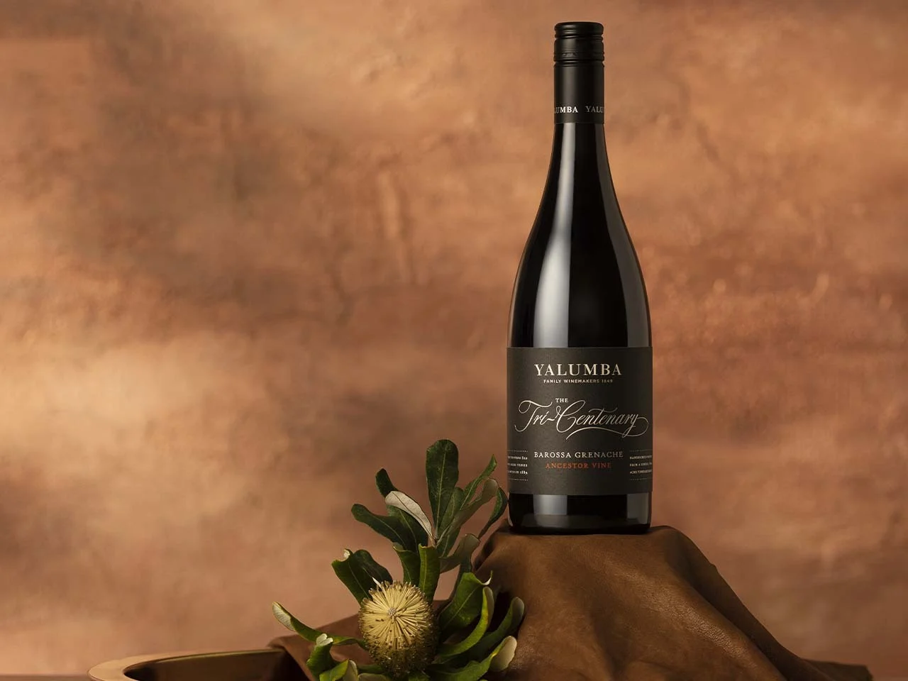 Tri-Centenary Grenache bottle with Australian native flower against terracotta background