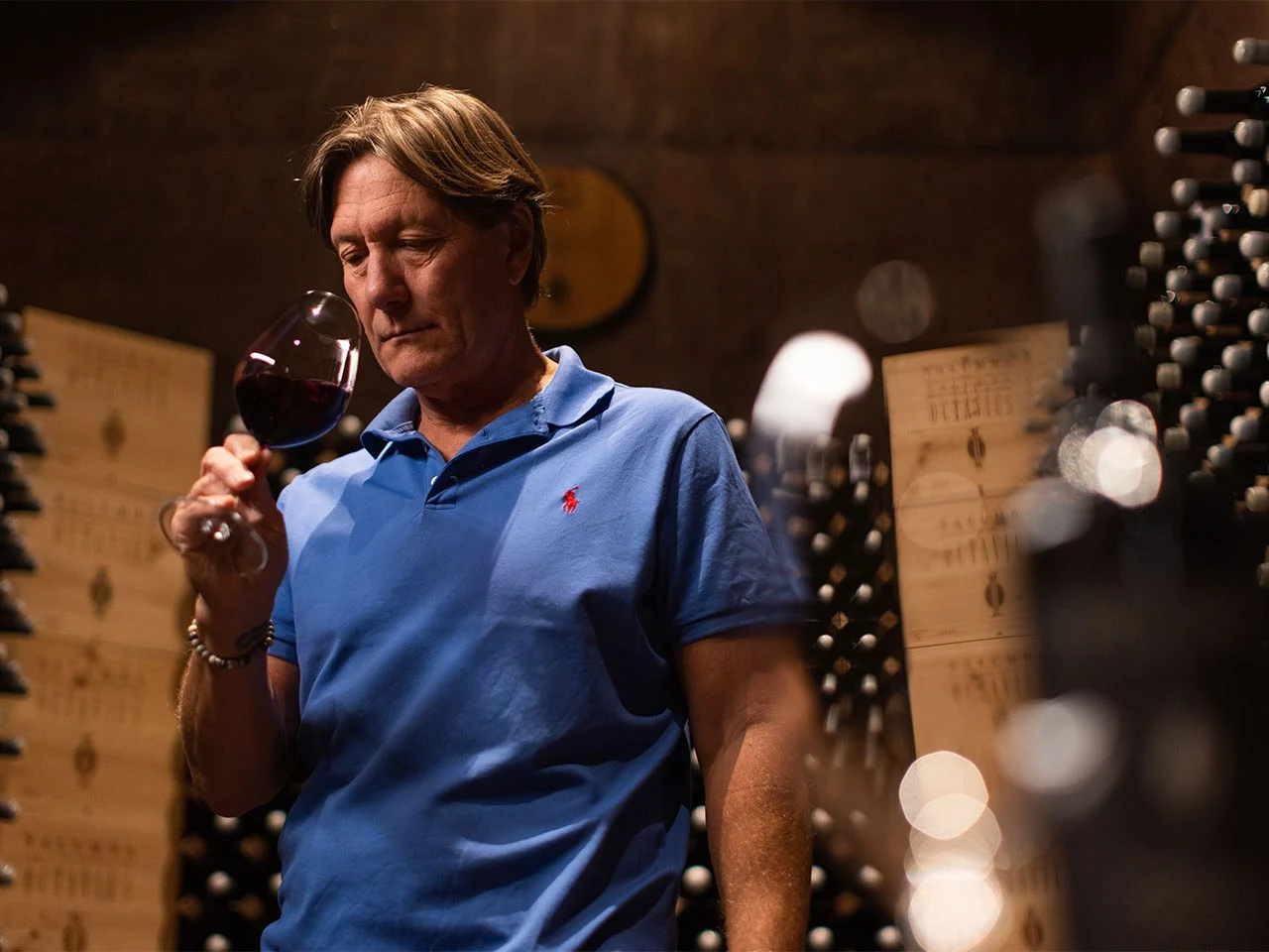 Winemaker examining red wine in glass in cellar
