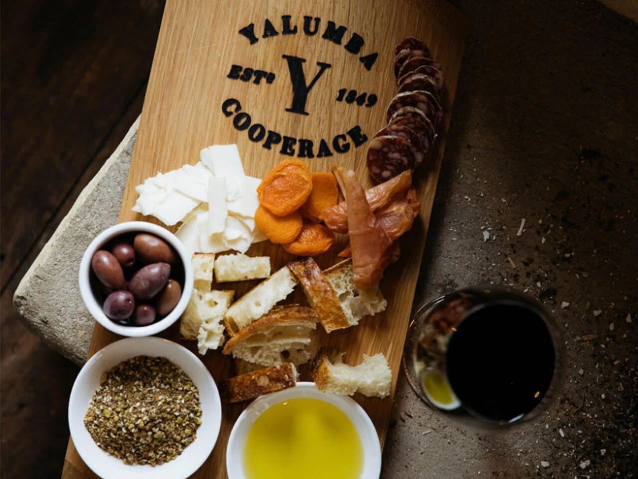 Artisanal food platter on Yalumba Cooperage branded wooden board with cheese, charcuterie, olives and wine