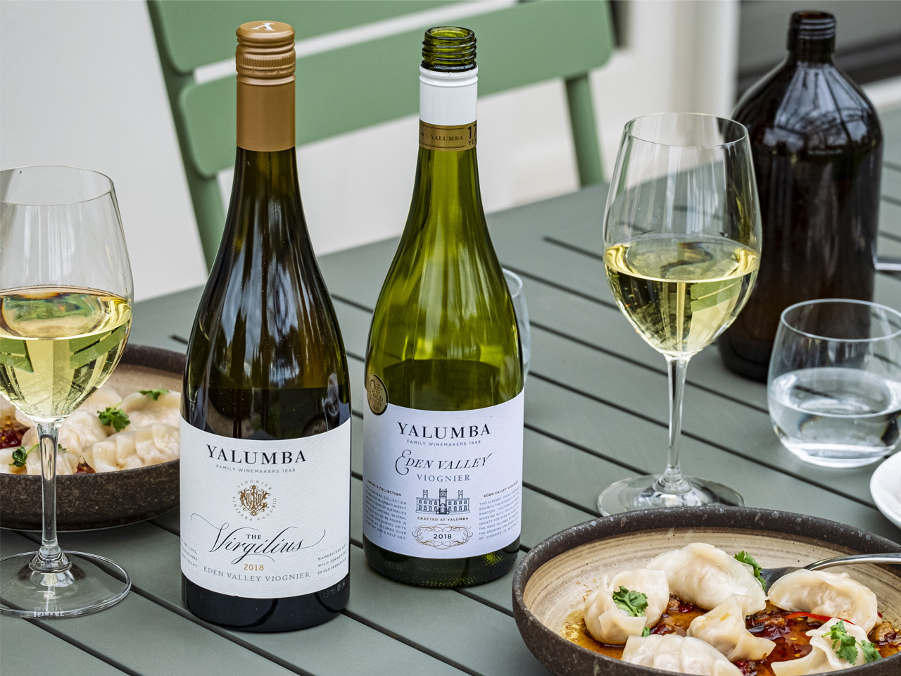 Bottles and glasses full of Yalumba Viognier sit amongst plates of dumplings in an outdoor setting