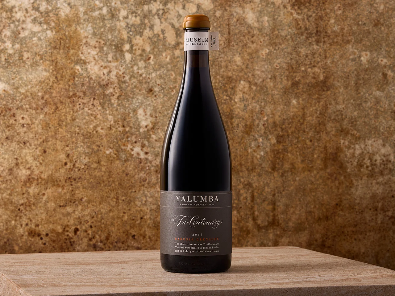 A bottle of Tri-Centenary Grenache sits on top of a wooden table