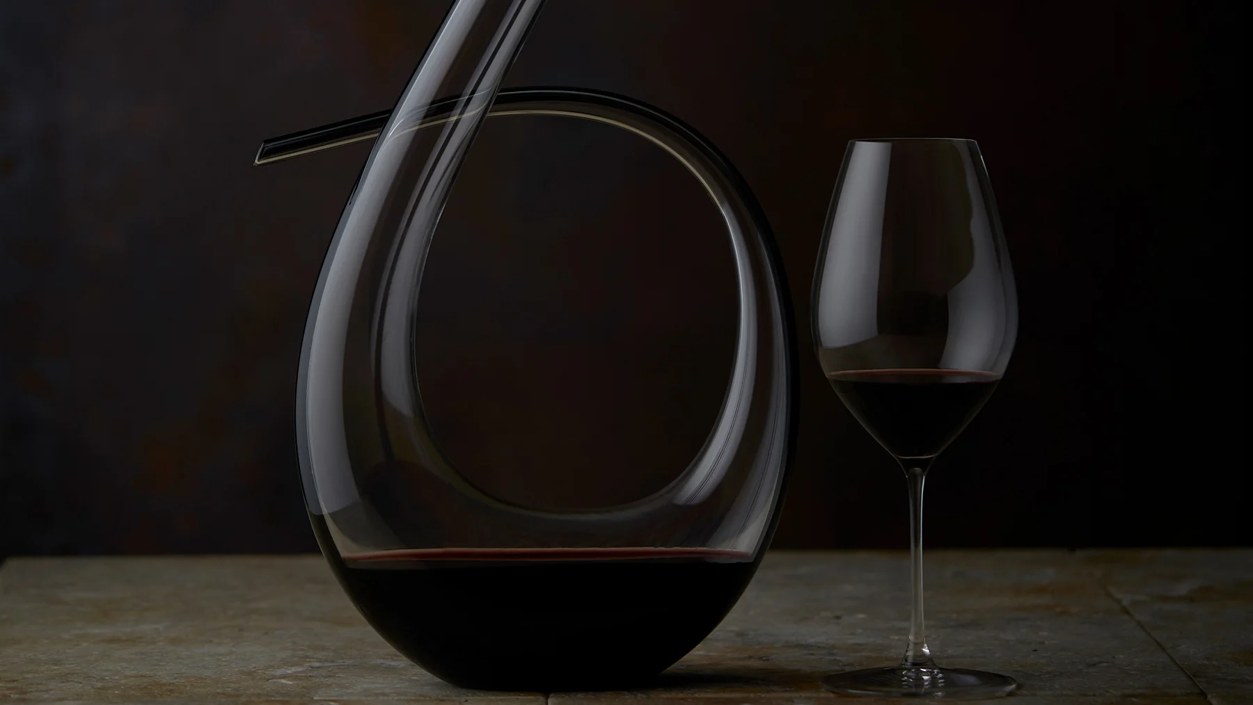 A classy decanter sitting alongside a glass filled with red wine