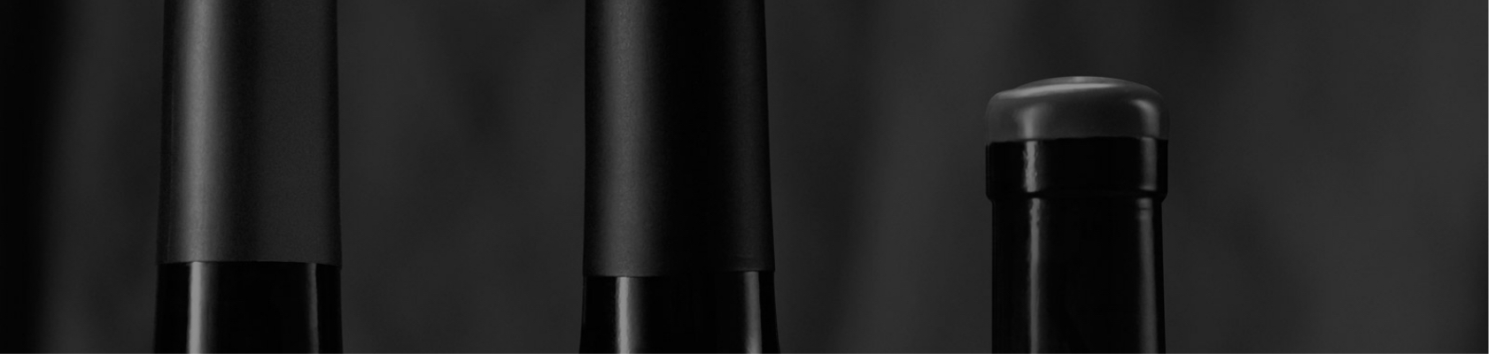 The necks of three red wine bottles