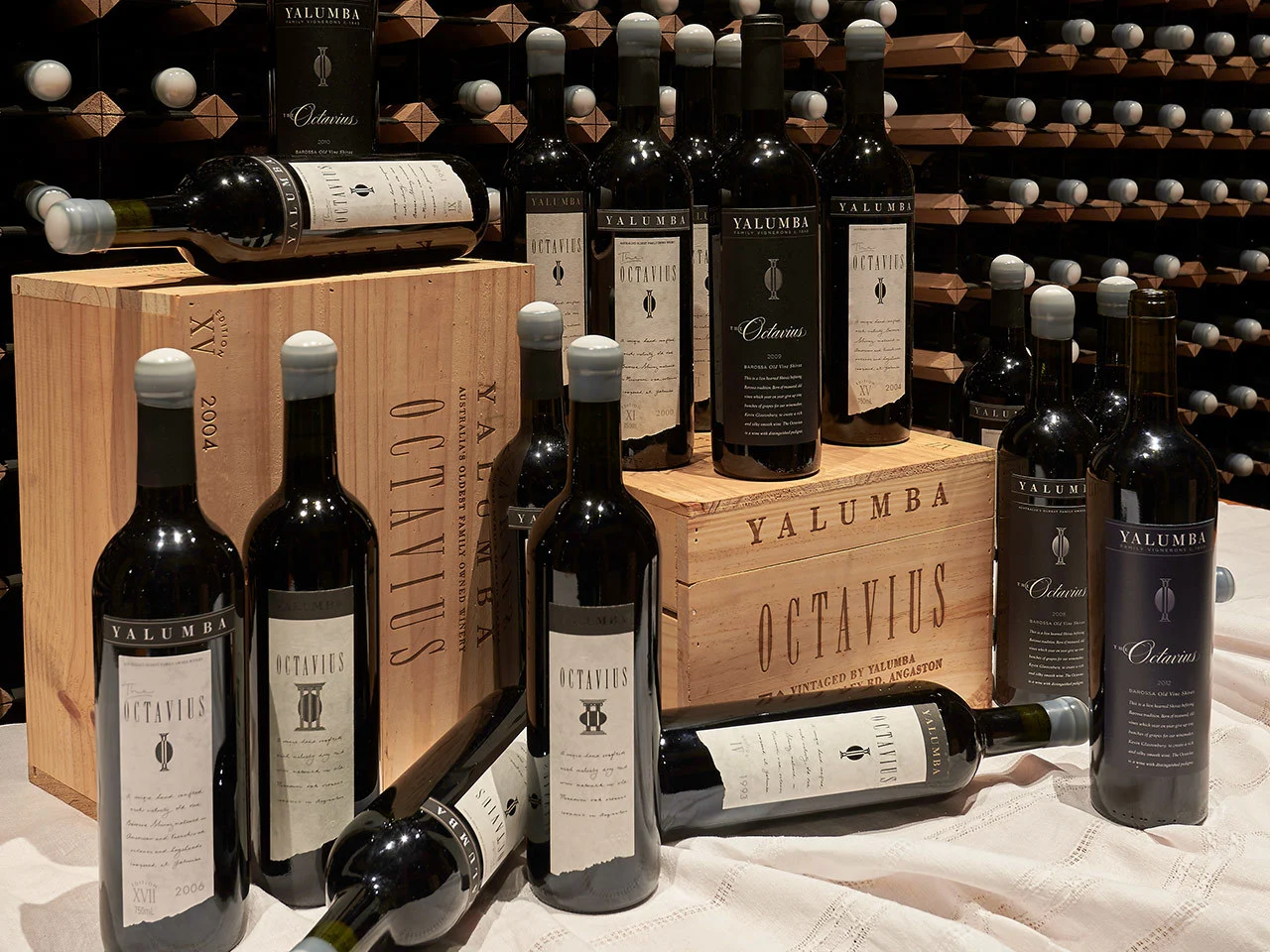 An array of Octavius bottles from different years, displayed in front of a classy wine rack