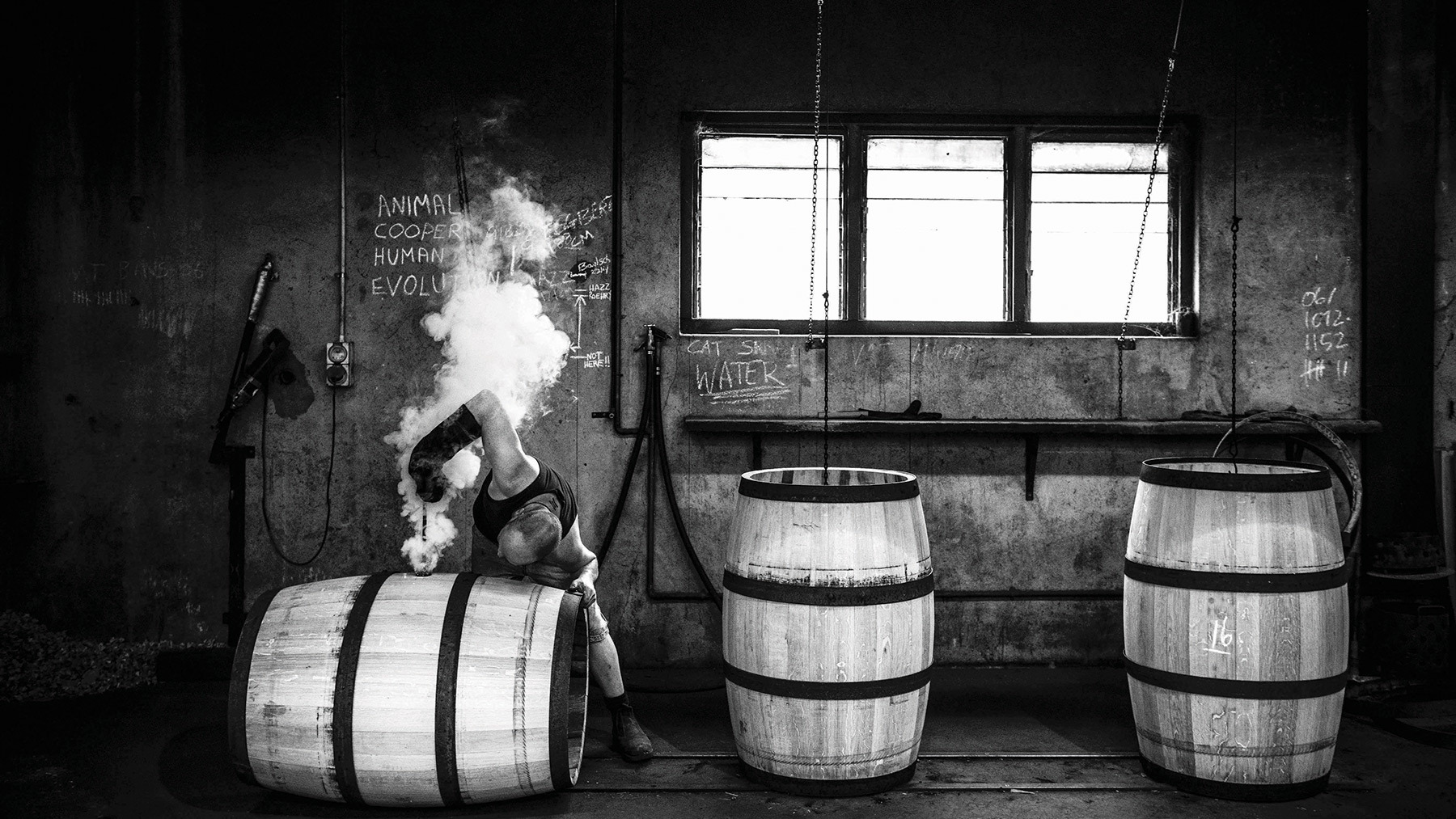 A person building a barrel by hand, putting the finishing touches on