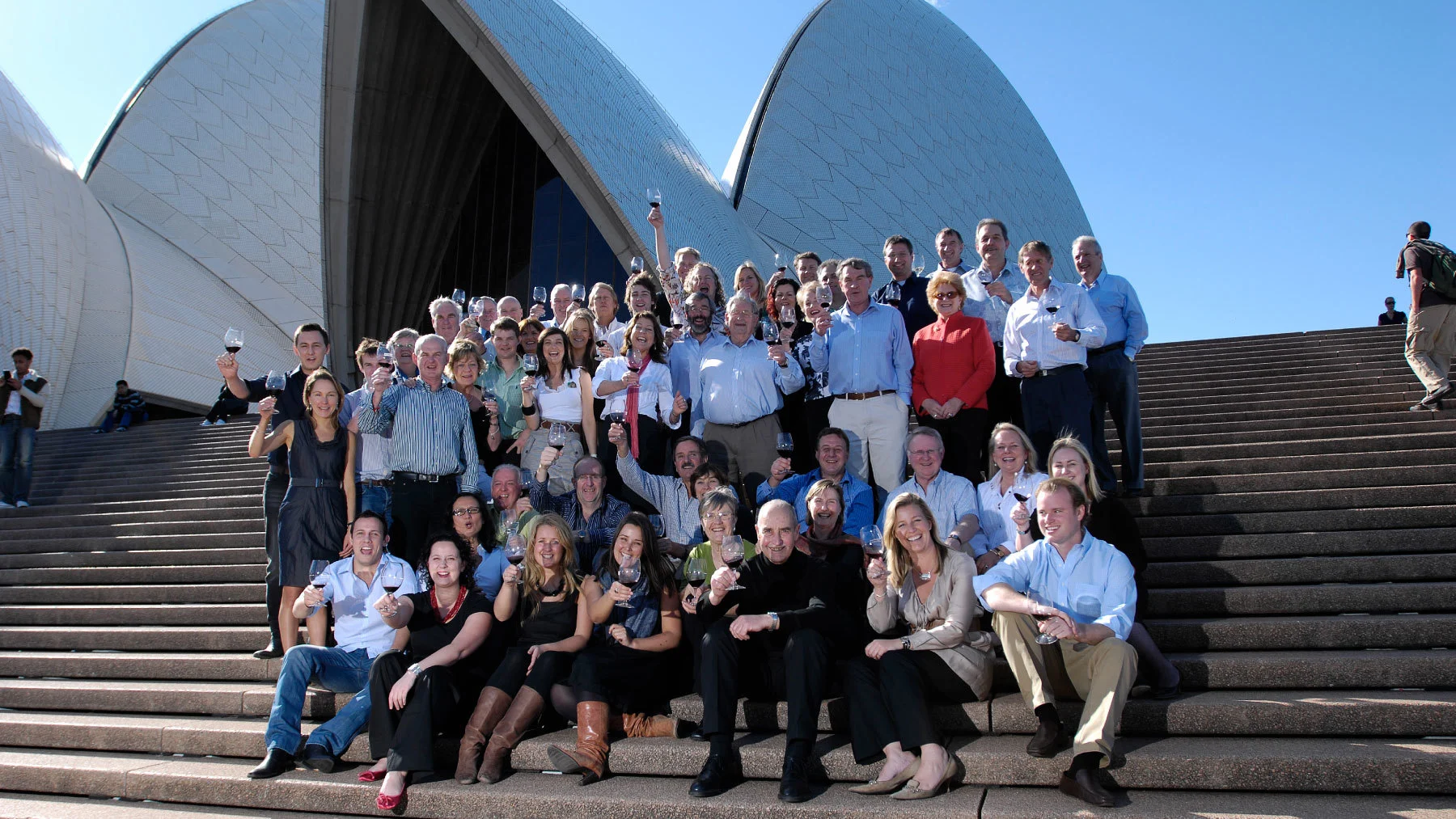 A photo of some of Australia's first winemaking families sitting outside the Sydney Opera House, drinking a glass of wine