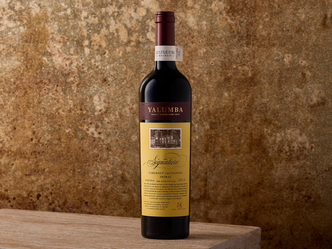 The Signature Cabernet Sauvignon and Shiraz bottle with distinctive yellow label against rustic background