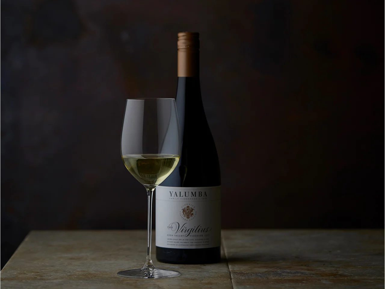 The Virgilius wine bottle with filled white wine glass on wooden surface