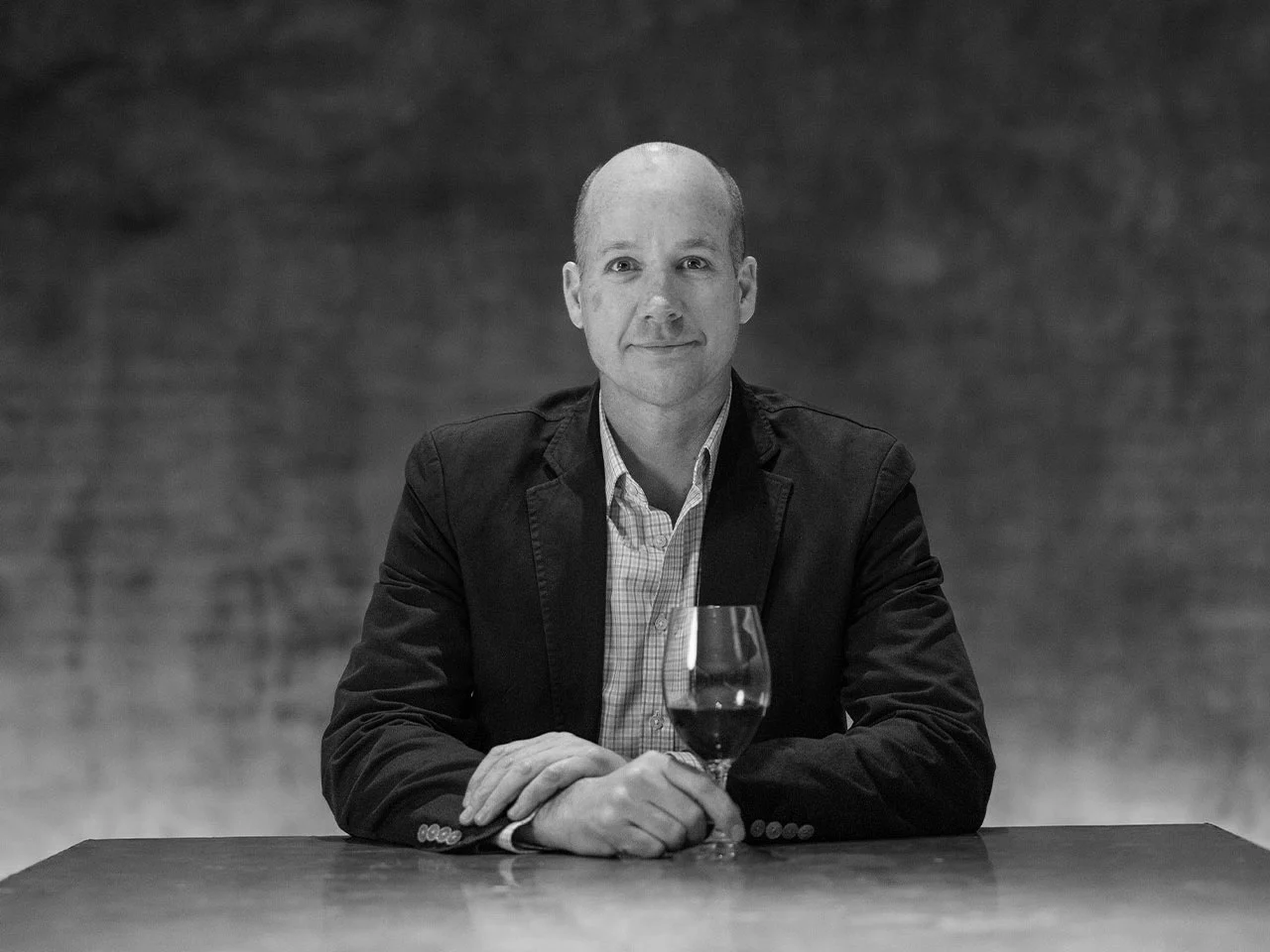 Black and white portrait of CEO Karl Martin with wine glass on table
